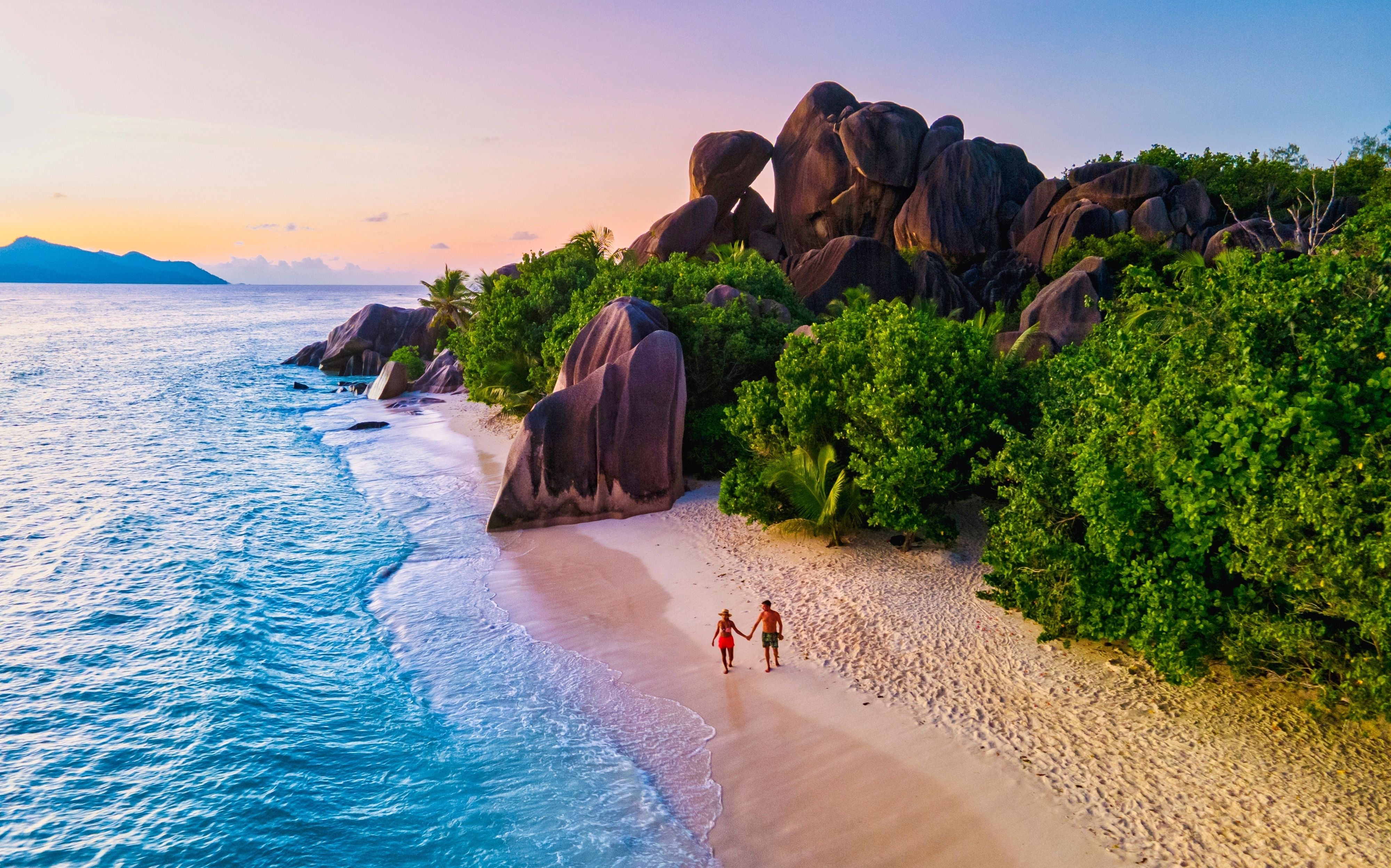 Par vandrer hånd i hånd på Anse Source d'Argent stranden på La Digue, Seychellerne