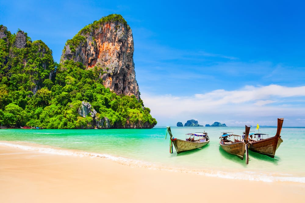 Farverige både ligger ved den smukke strand omgivet af majestætiske kalkstensklipper og krystalklart vand. Et tropisk paradis i Thailand, der indbyder til snorkling, sejlads og uforglemmelige naturoplevelser.