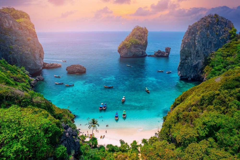 Luftfoto taget med drone af den turkisblå lagune ved Nui Beach på Koh Phi Phi, Thailand. Smukt landskab med krystalklart vand, hvid sandstrand og frodig tropisk natur – et paradisisk rejsemål for strandelskere og eventyrrejsende.