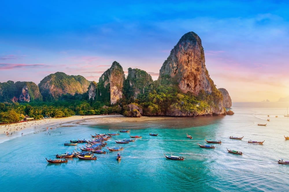 Railay Beach i Krabi, Thailand – tropisk strand med traditionel longtail-båd, klart vand og dramatiske klipper.