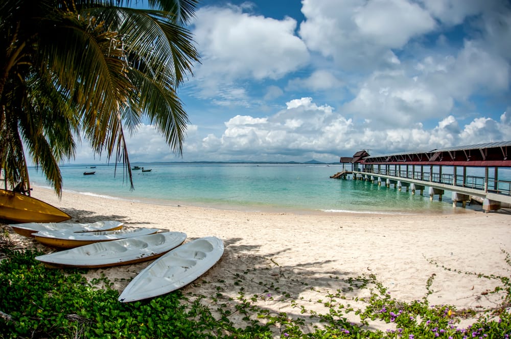 Fisheye-udsigt af kajakker fortøjet ved en mole – idyllisk kystscene med klar himmel og roligt vand