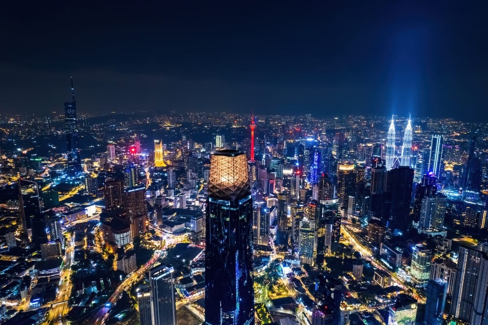 Smuk naturscene af Kuala Lumpur by om natten – oplyste skyskrabere, moderne bylandskab og ikoniske vartegn som Petronas Towers. » Tembo Travel Smuk naturscene af Kuala Lumpur by om natten – oplyste skyskrabere, moderne bylandskab og ikoniske vartegn som Petronas Towers.
