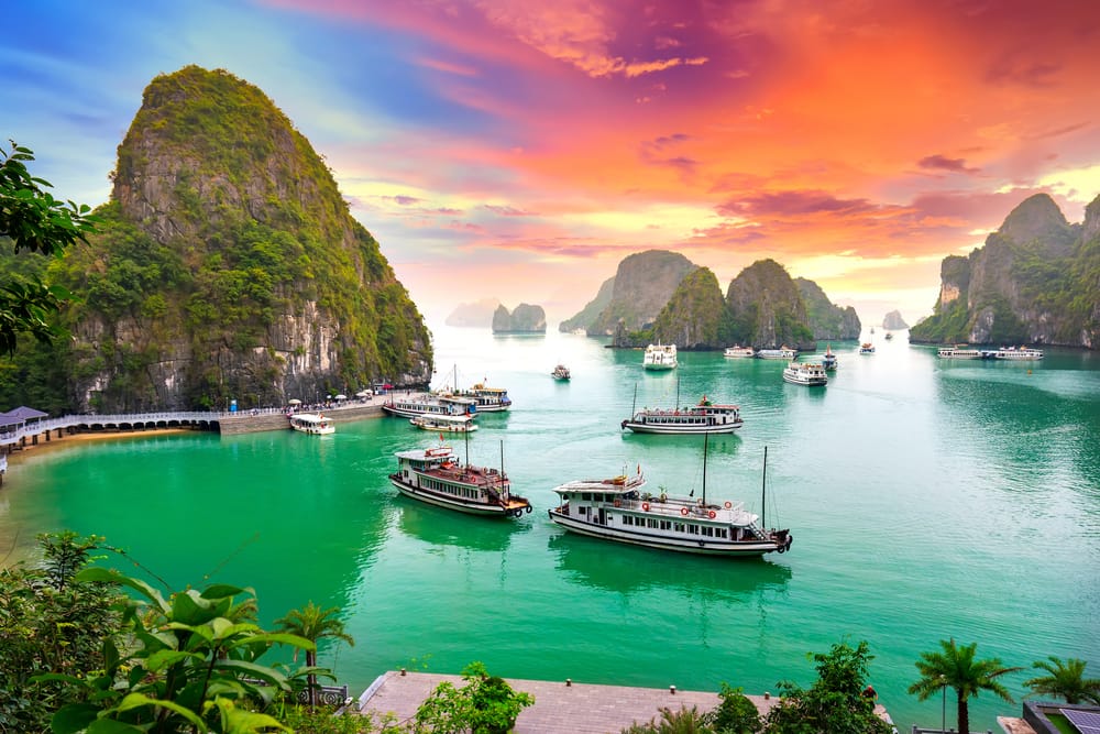 Drømmende solnedgang over Halong Bay i Vietnam – set fra oven med udsigt til de ikoniske kalkstensøer badet i varme, gyldne nuancer.