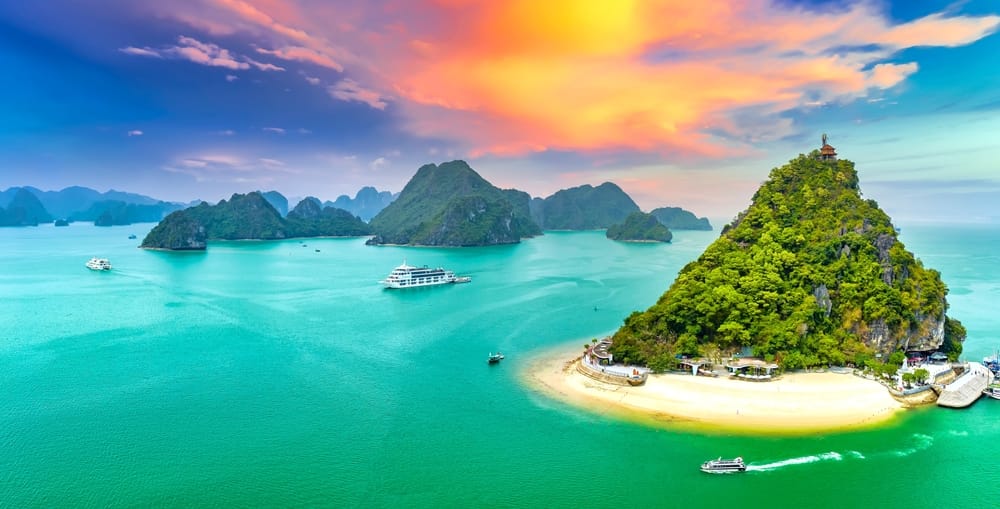 Drømmende solnedgang over Halong Bay i Vietnam – de ikoniske kalkstensøer spejler sig i havets varme nuancer. » Tembo Travel Drømmende solnedgang over Halong Bay i Vietnam – de ikoniske kalkstensøer spejler sig i havets varme nuancer.