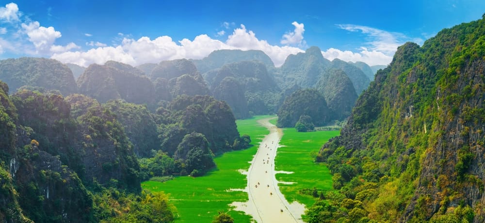 Landskab fra Tam Coc i Ninh Binh, Vietnam – majestætiske bjerge rejser sig over frodige rismarker og snor sig langs stille floder.