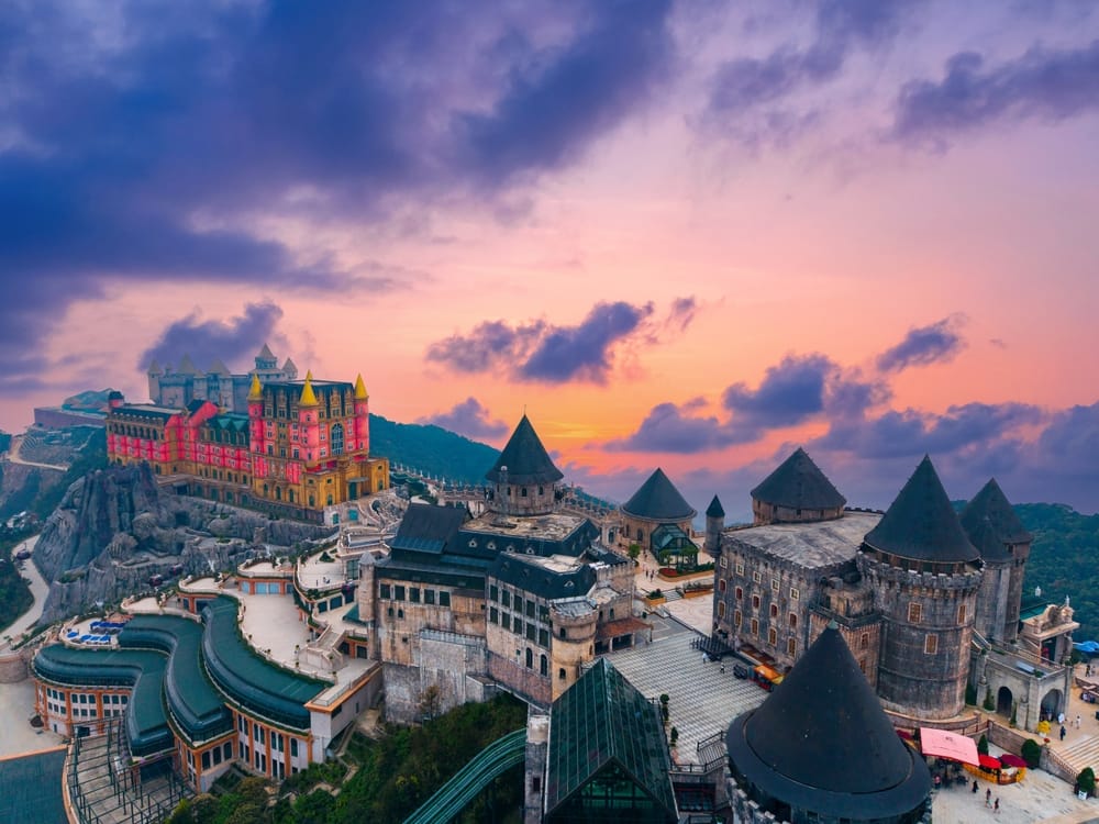 Solopgang over Ba Na Hills nær Da Nang, hvor eventyrlige slotte og det omkringliggende bjerglandskab bades i gyldent morgenlys.