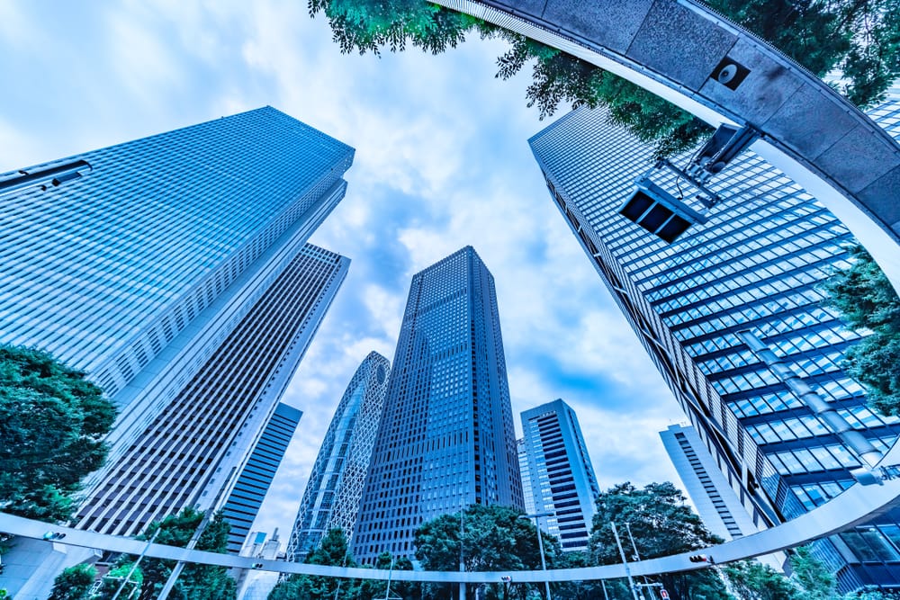 Shinjuku i Tokyo, Japan – moderne skyskrabere omgivet af friske grønne træer på en overskyet dag.