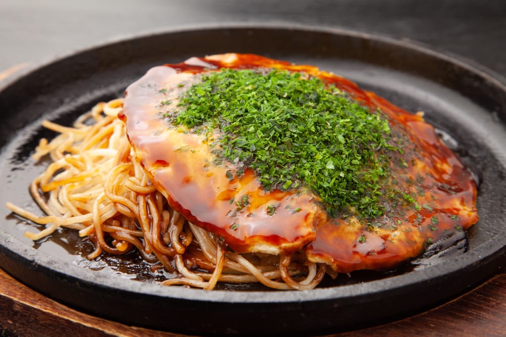 Hiroshima-style okonomiyaki – en japansk, fyldig pandekage lag på lag med kål, nudler og lækre toppings.