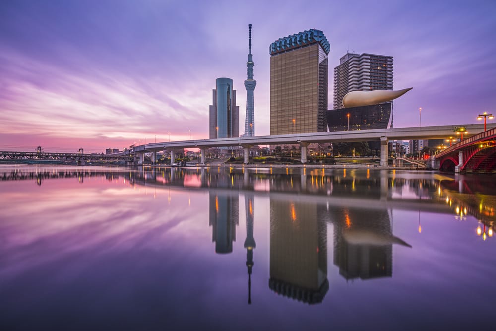 Udsigt over Tokyos skyline langs Sumida-floden, Japan, med moderne højhuse og flodens rolige vand i forgrunden