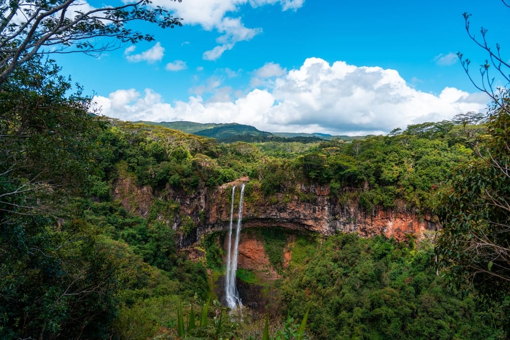 Panoramisk udsigt over Chamarel-vandfaldet på Mauritius, der falder ned i den frodige dal.