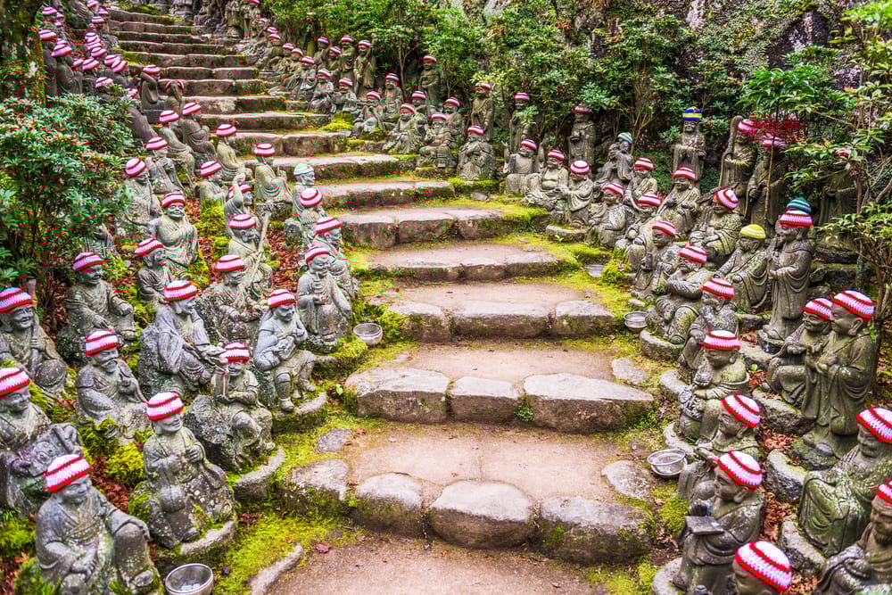 Miyajima Island ved Hiroshima, Japan – stemningsfulde stier flankeret af Buddha-statuer i naturskønne omgivelser.