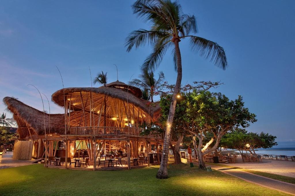 Strandrestaurant ved Merusaka Hotel, Nusa Dua, Bali, Indonesien – bambusbygning oplyst ved solnedgang med havudsigt.