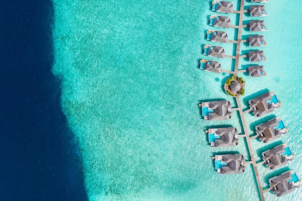 Luftfoto af Overwater Villas i turkis lagune på Finolhu Maldiverne.