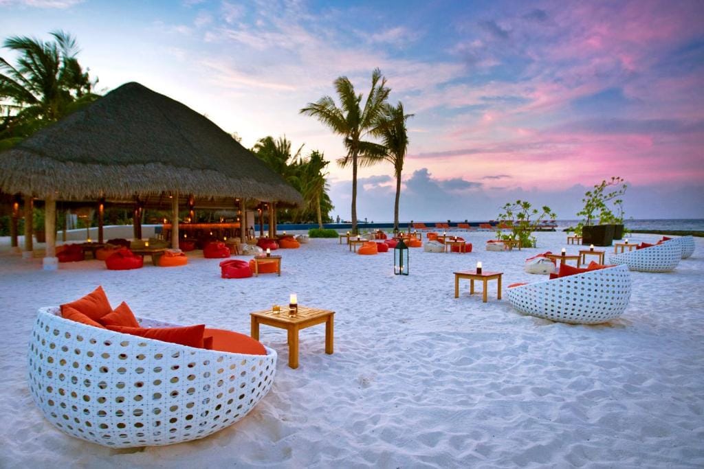 Strandbar på Kuramathi Maldives med loungemøbler og solnedgang.