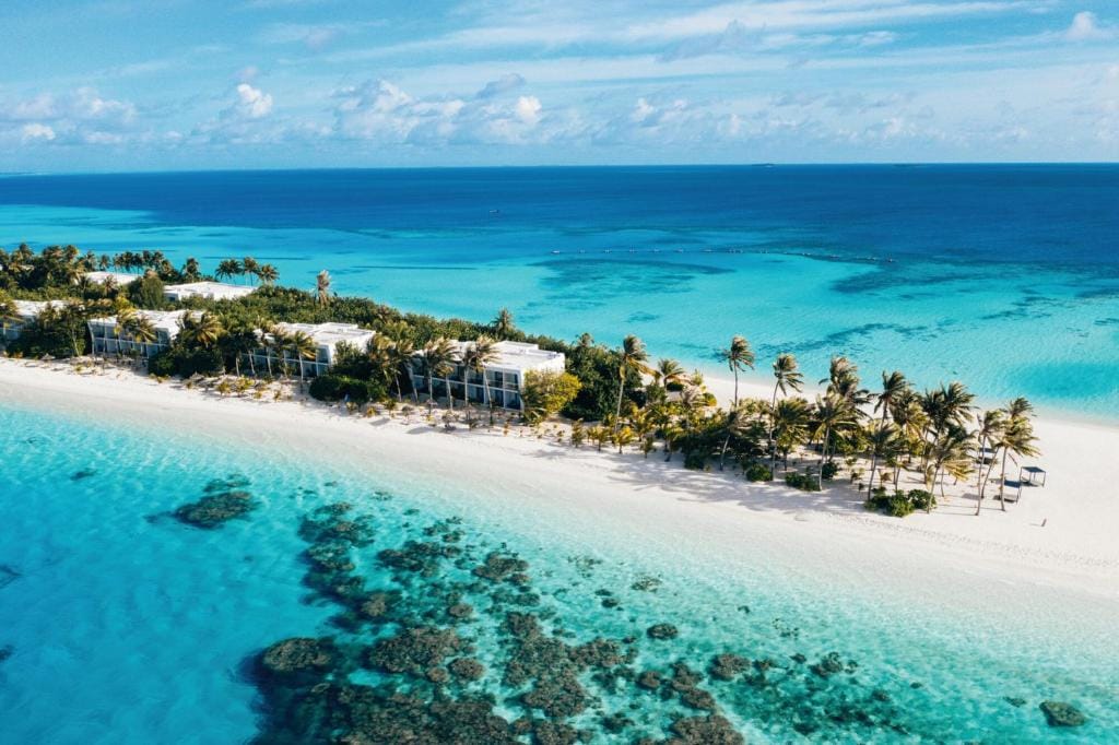 Luftfoto af RIU Atoll med strand, palmer og turkis lagune.