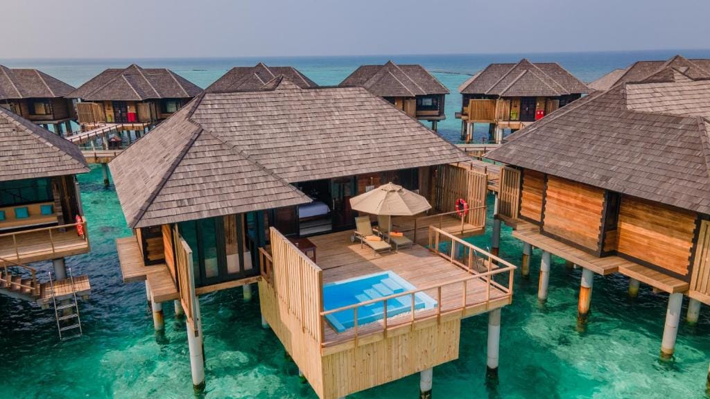 Overwater villas på Sun Siyam Iru Fushi med private terrasser og pools over det turkisblå hav.