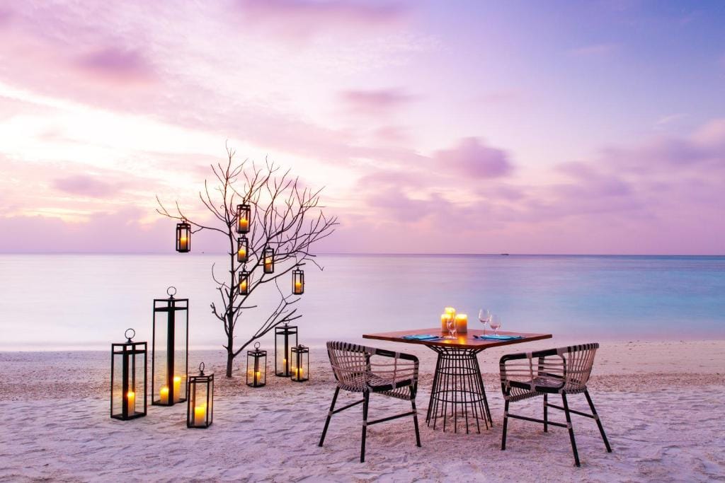 Romantisk middagsbord med lanterner på stranden ved solnedgang på Kandima Maldives