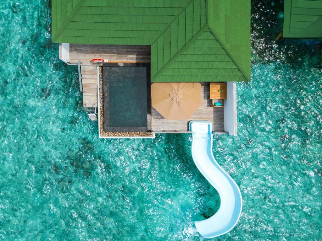 Luftfoto af vandvilla på Siyam World med privat pool, solterrasse og rutsjebane ned i det turkisblå hav.