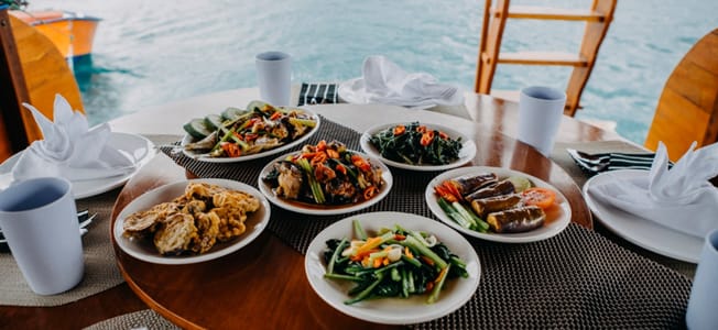 Frisklavet indonesisk mad på White Pearl 02, serveret på dækket med udsigt over havet i Komodo National Park, Indonesien.