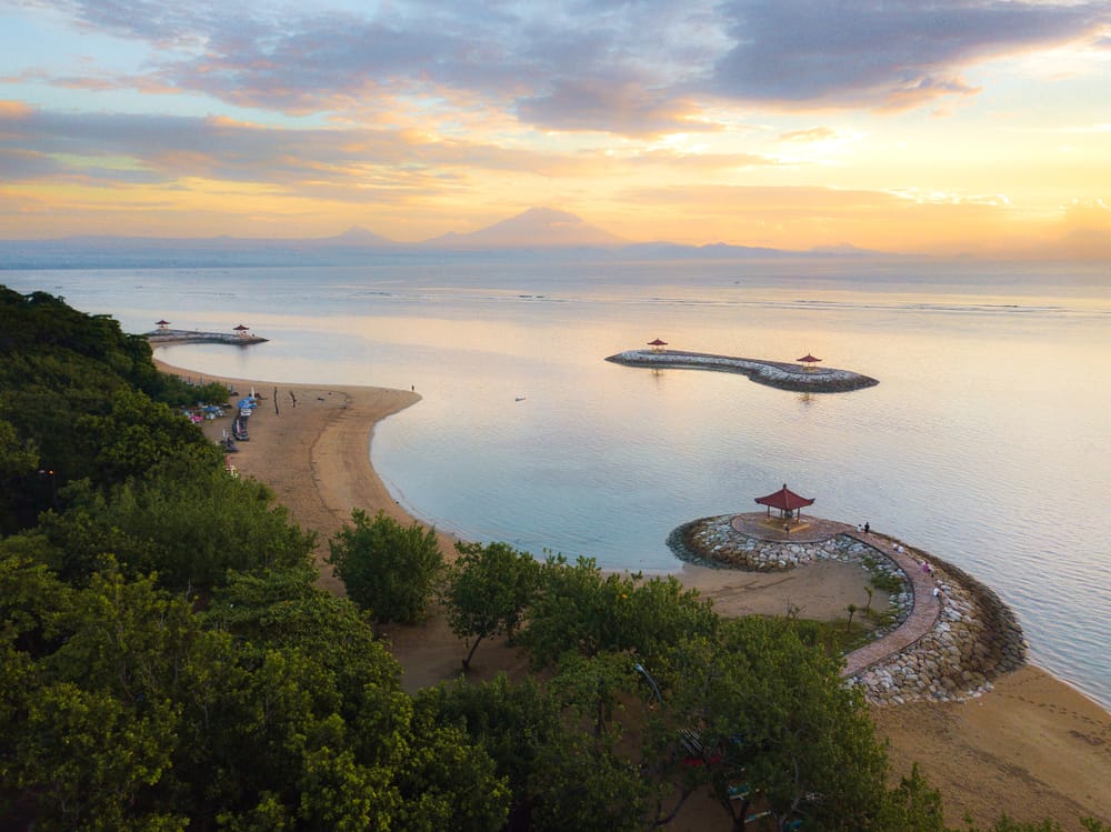 Solopgang ved Karang Beach, Bali, Indonesien, med udsigt til vulkanen Mount Agung og det rolige hav.