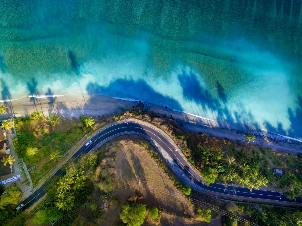 Kystvej i bjergene ved Senggigi Beach, Lombok, Indonesien, med udsigt til havet og blå sommerhimmel.