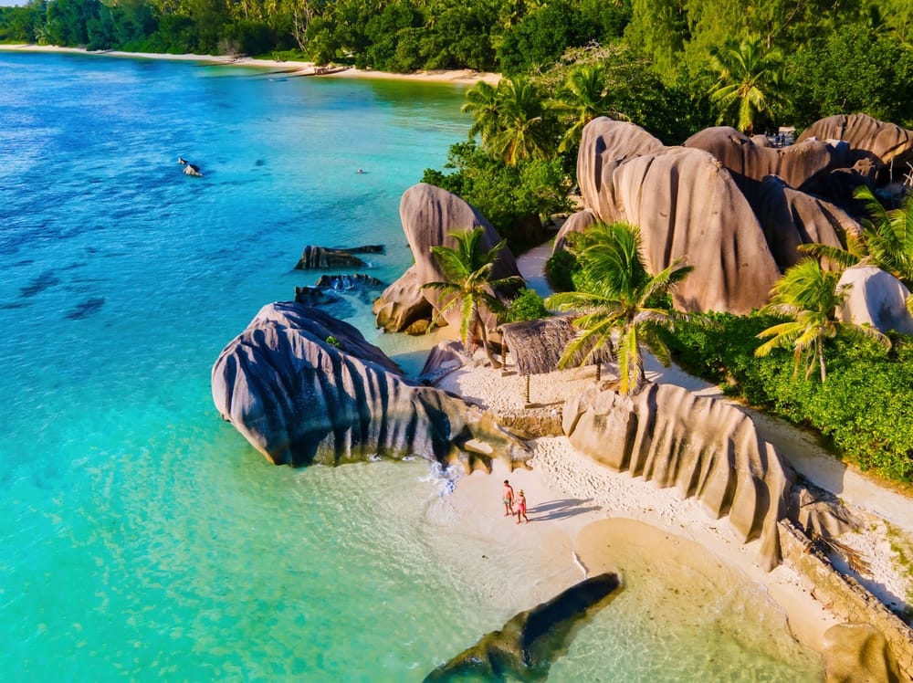Anse Source d’Argent Beach, La Digue Island, Seychellerne, set fra luften – turkist vand, palmer, og ikoniske granitklipper i et tropisk paradis.