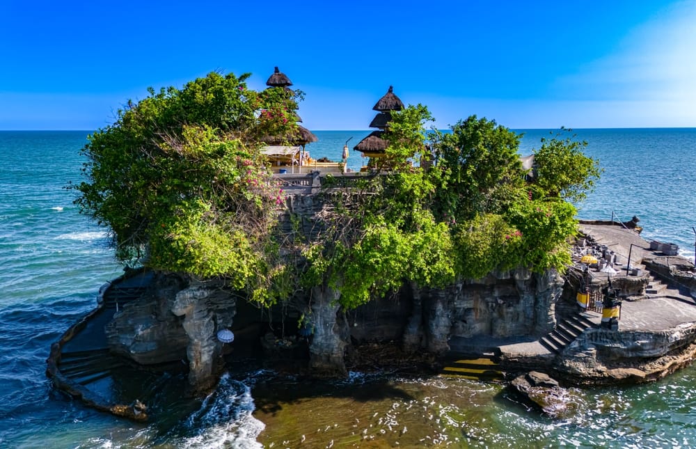 De majestætiske klipper ved Tanah Lot – hvor havet møder templet, og solnedgangen maler himlen gylden over Balis kyst.