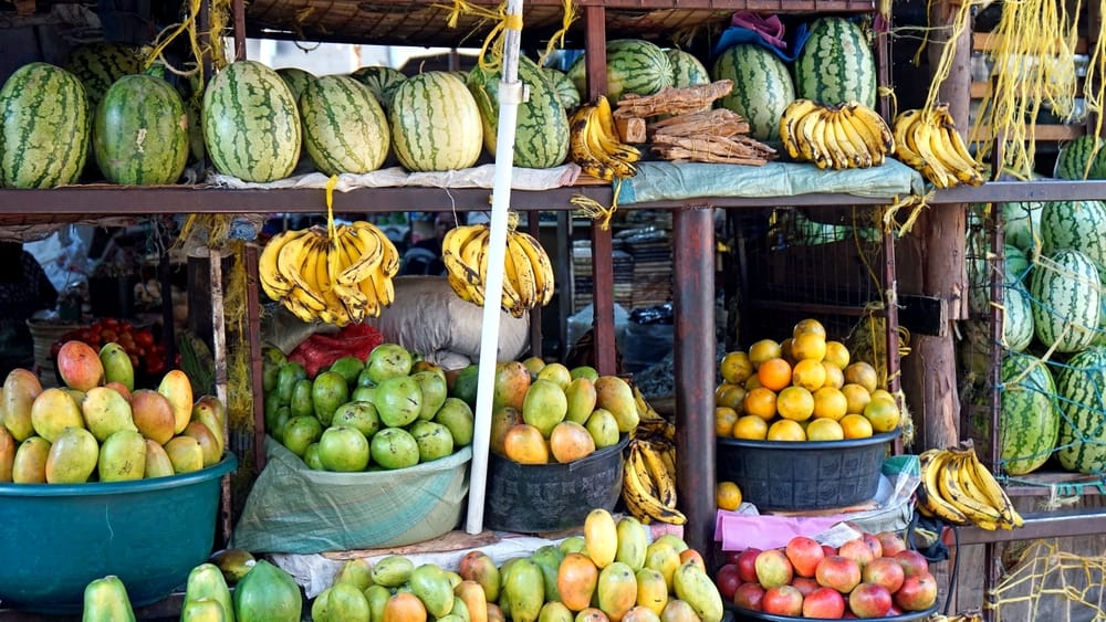 Farverige frugter på et lokalt marked på Zanzibar – mango, ananas og papaya fylder boderne med duft og tropisk stemning.
