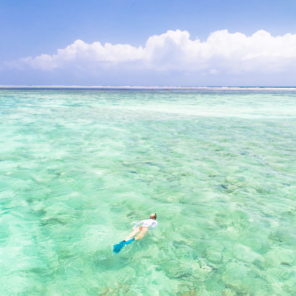 Kvinde snorkler i det klare, lavvandede hav ud for Mnemba Island på Zanzibar.