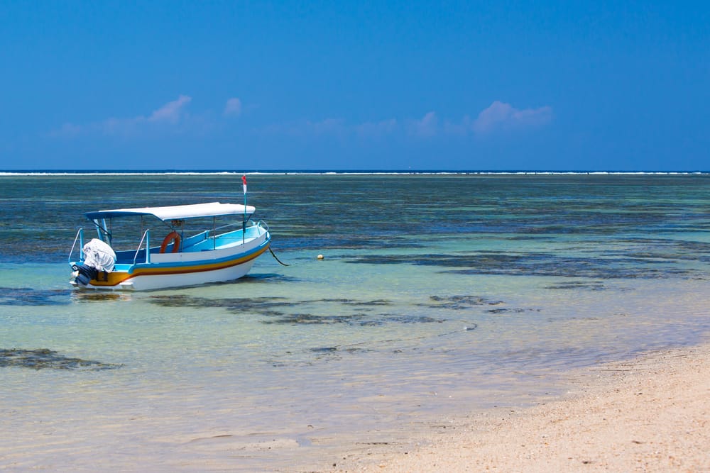 Traditionel balinesisk fiskerbåd fortøjet ved Sanur Beach – et fredfyldt øjeblik i morgenlyset over havet.