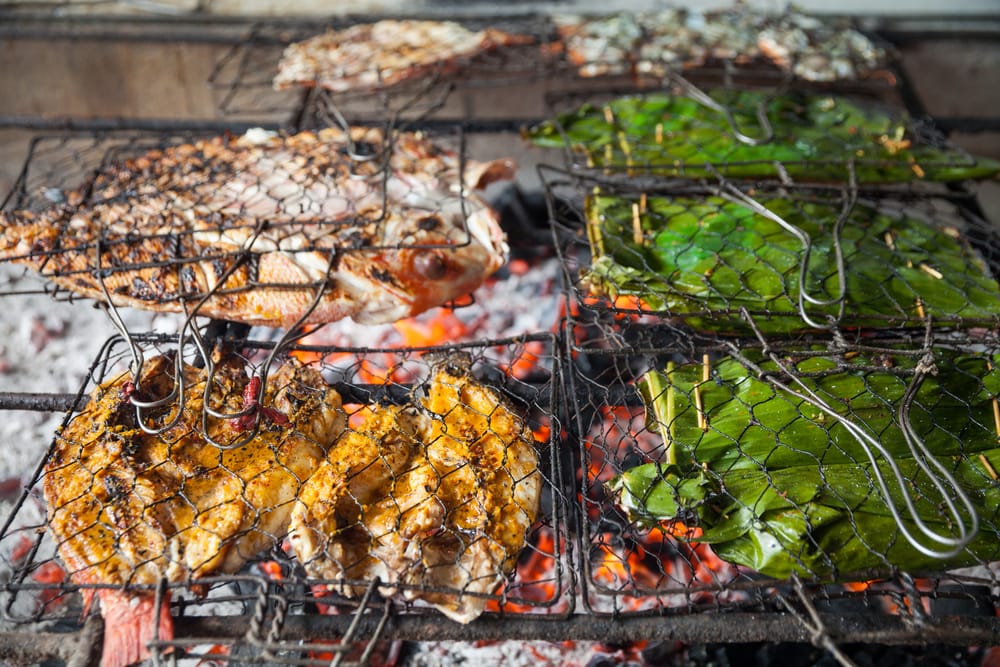 Grillet frisk fisk og skaldyr – papegøjefisk, blæksprutte og rejer serveret direkte fra grillen ved stranden på Bali.