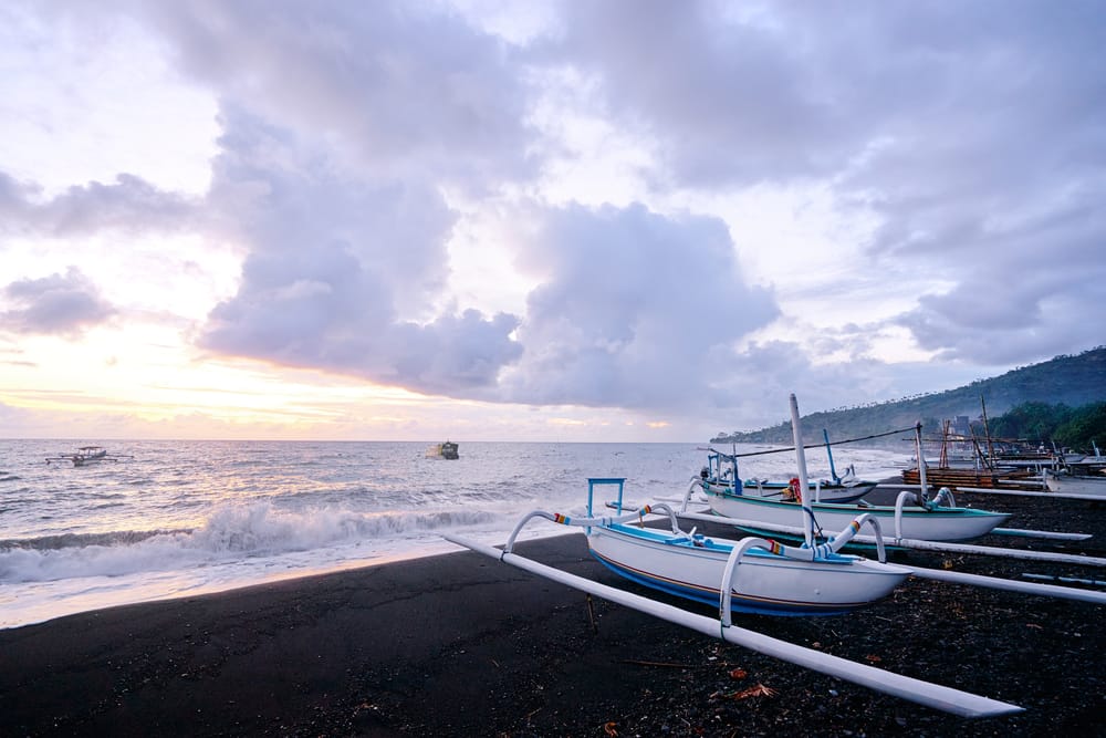 Solopgang over Lovina Beach, Bali, Indonesien, med traditionelle fiskerbåde på havet og blødt gyldent lys.