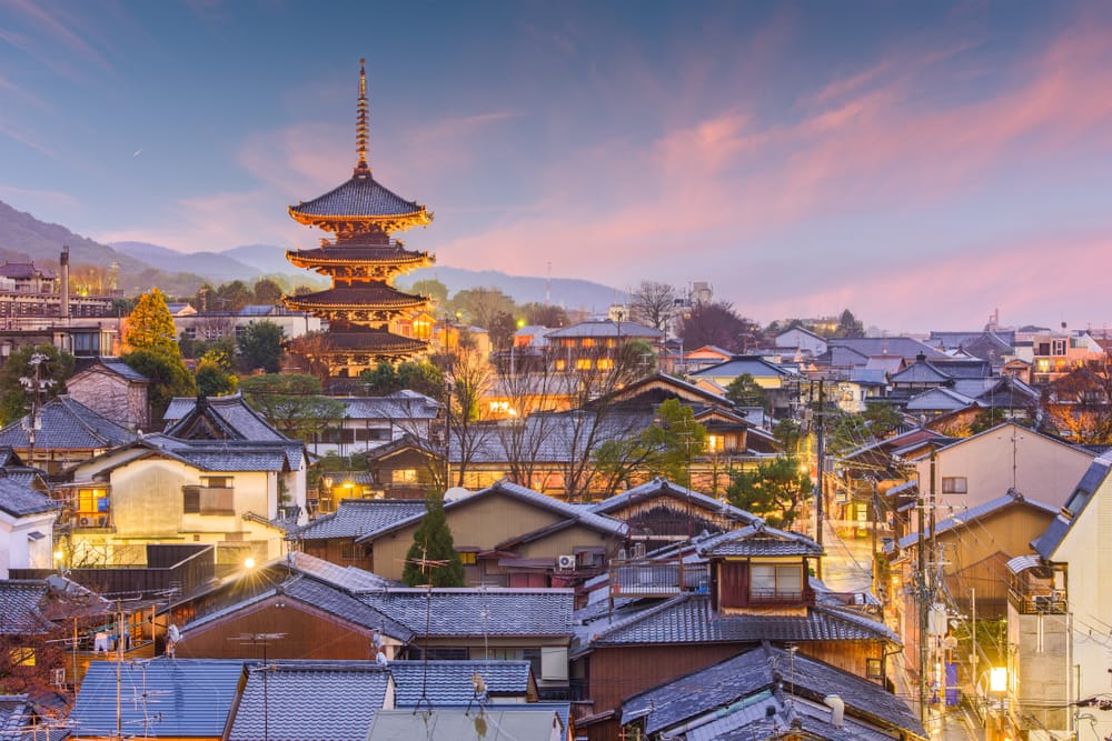 Aftenstemning over Kyoto med udsigt til Yasaka-pagoden omgivet af traditionelle japanske huse og oplyste gader i Higashiyama-distriktet.