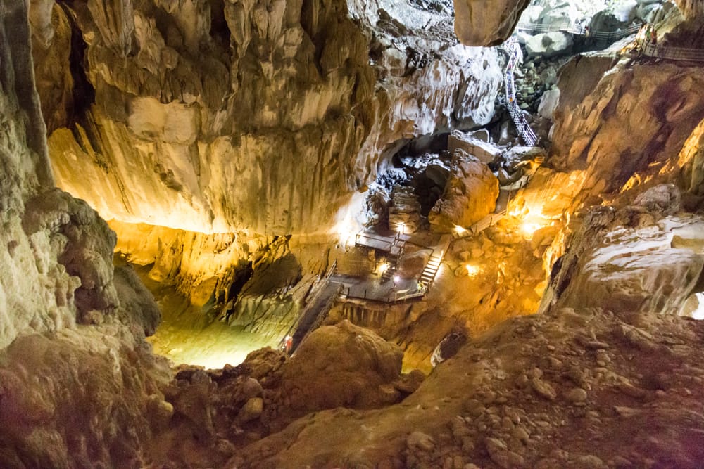 En imponerende klippehal i Clear Water Cave i Mulu Nationalpark, hvor en plankesti fører besøgende gennem de mægtige kalkstensformationer og det underjordiske landskab.