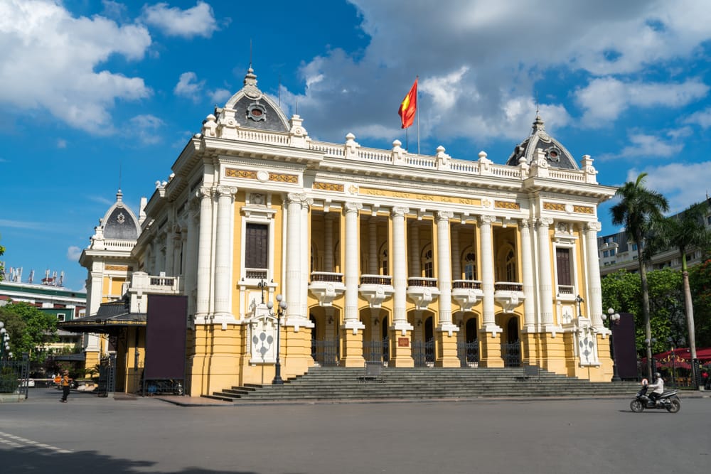 Franskbygget operahus i Hanoi med blå himmel, klassiske søjler og kolonial arkitektur
