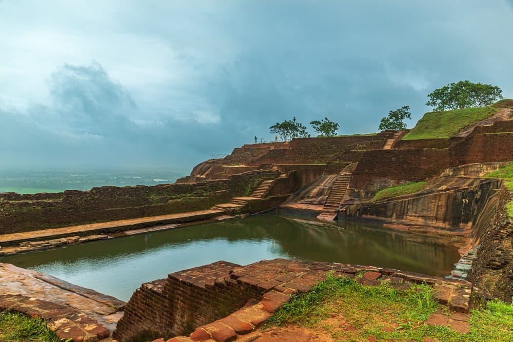 Stenbassiner og vandkanaler ved Sigiriya Rock Fortress omgivet af grønne haver i Sri Lanka.