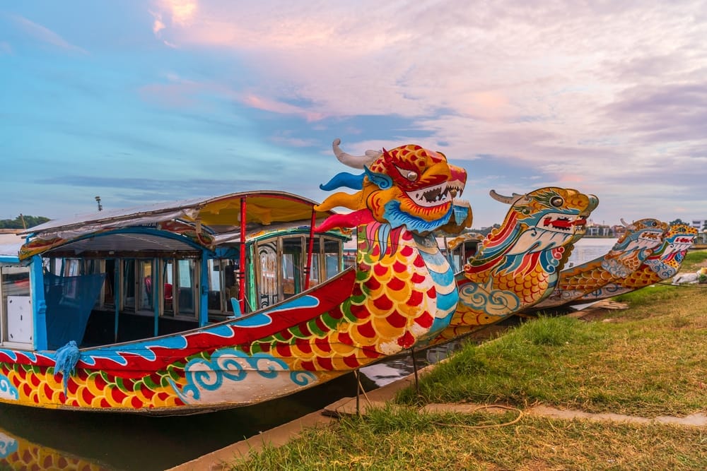 Traditionel dragebåd på Parfume-floden i Hue, Vietnam, ved skumringstid.
