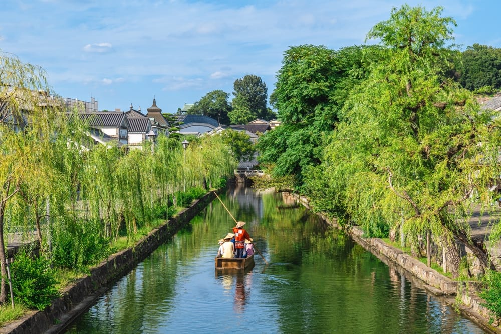 Kurashiki Bikan Historical Quarter i Okayama med traditionelle hvide kura-huse langs en rolig kanal omgivet af piletræer og historiske bygninger.