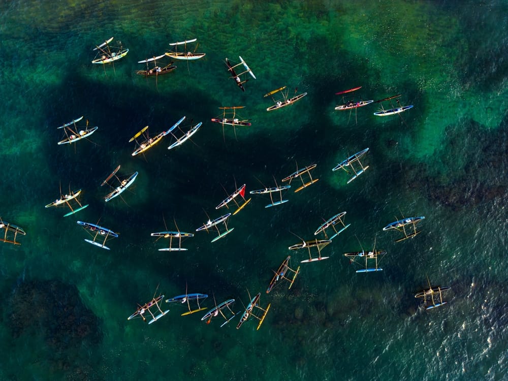 Luftfoto af traditionelle oruwa-kanoer med fiskere på en sø omgivet af frodig tropisk natur i Sri Lanka.