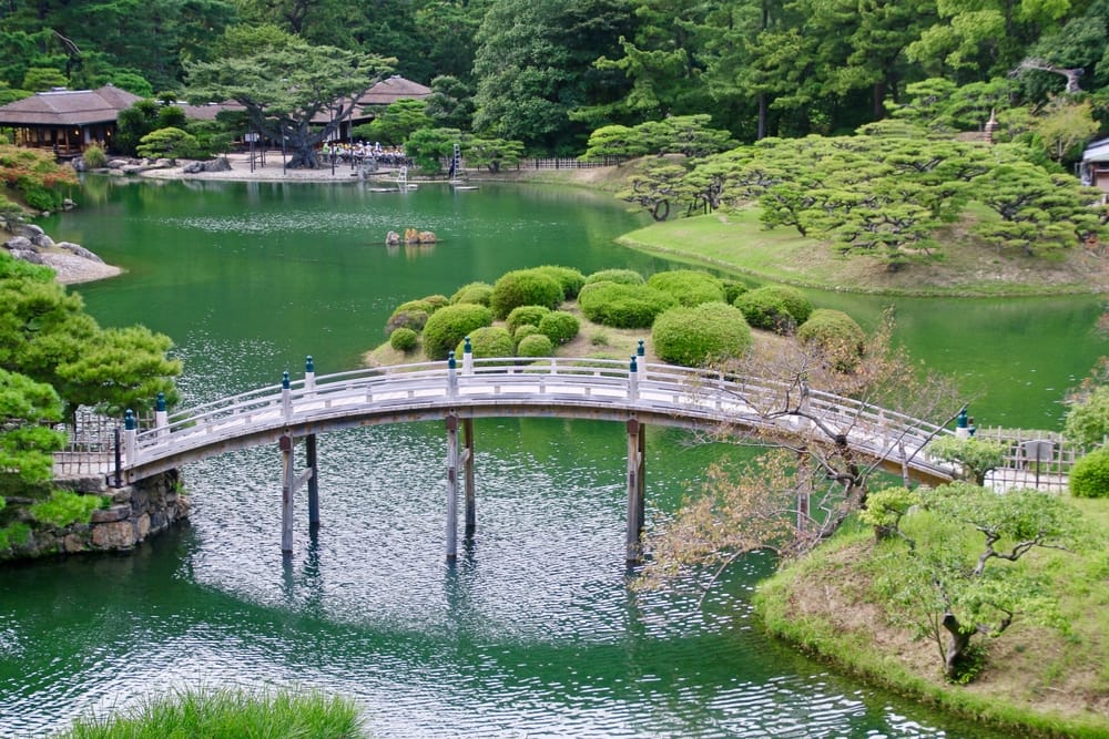 Ritsurin Garden i Takamatsu med damme, formklippede fyrretræer og traditionelle tehus omgivet af smuk japansk havearkitektur.