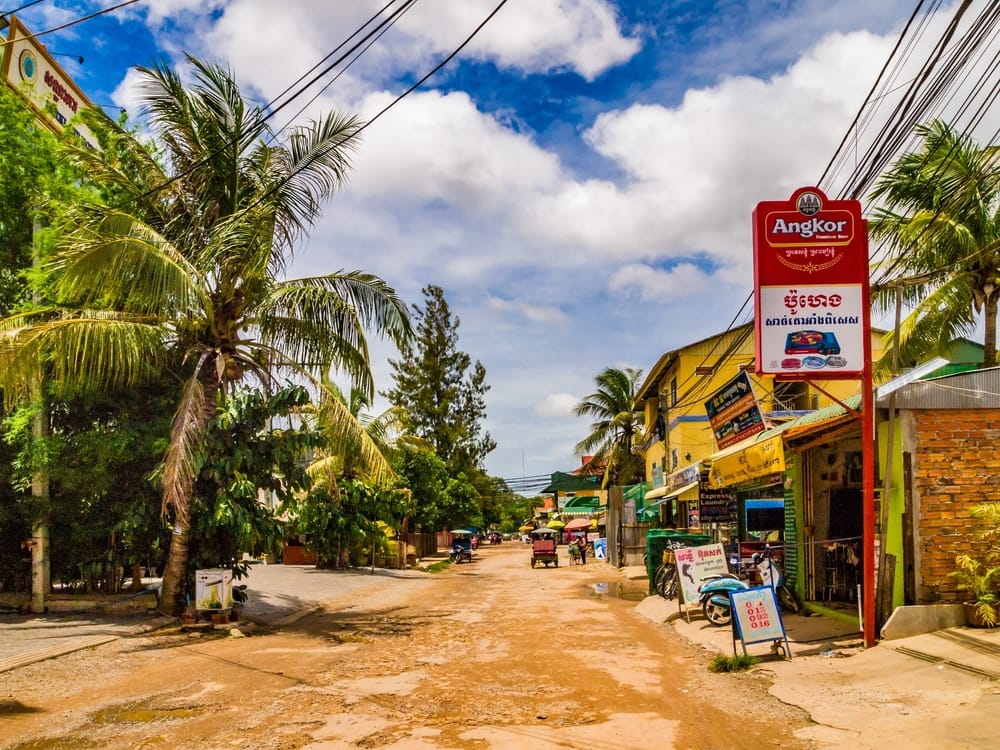Gadebillede fra Siem Reap, Cambodja, med butikker, tuk-tuks og lokale i gadelivet