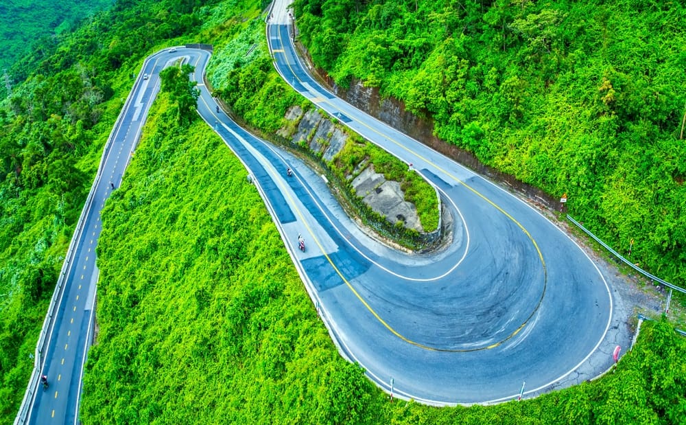 Luftfoto af Hai Van-passet i Vietnam med snoet bjergvej, kystlinje og frodig natur mellem Huế og Da Nang.