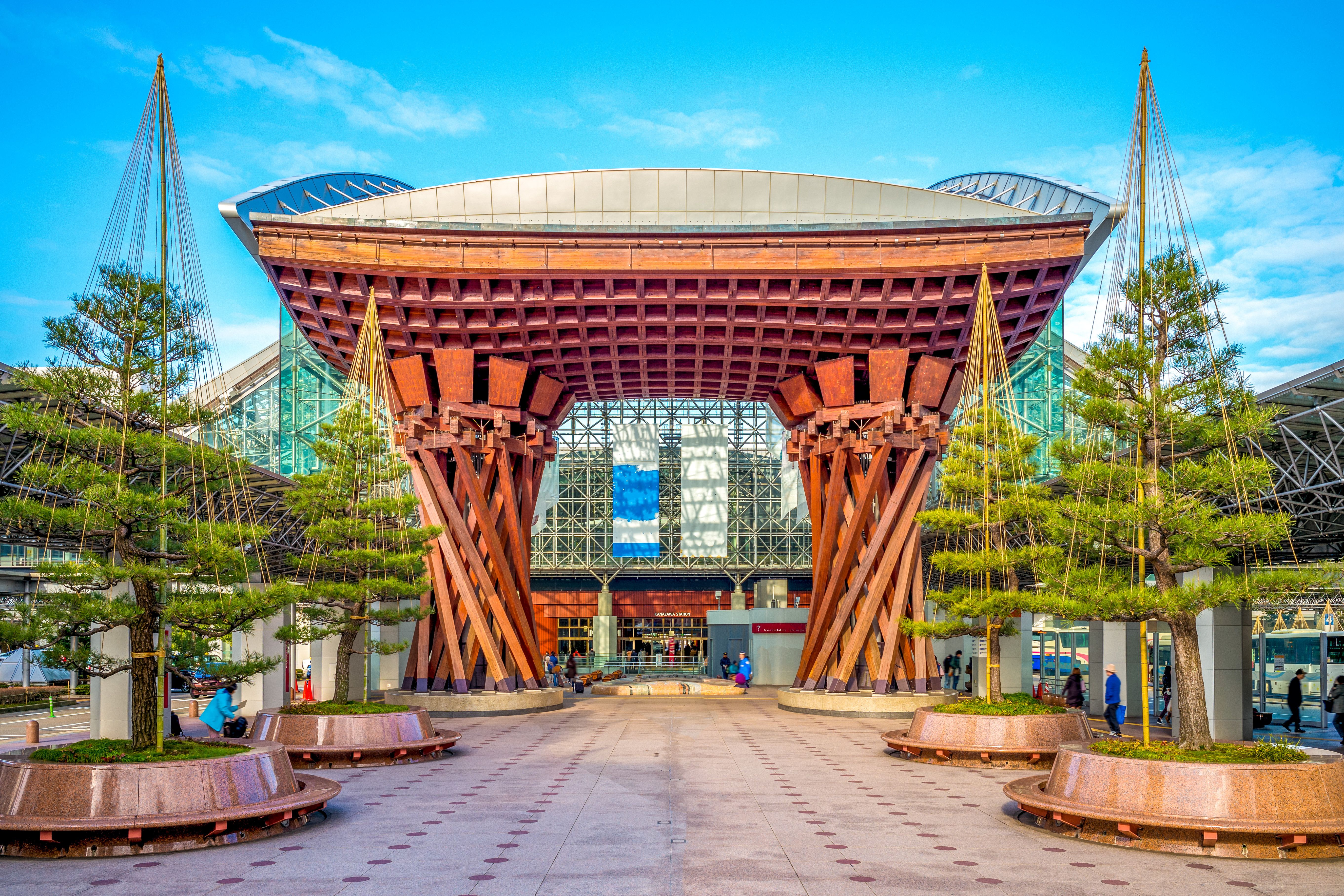 Den ikoniske Drum Gate ved Kanazawa Station med sine store træbuer og moderne glasfacade i baggrunden.