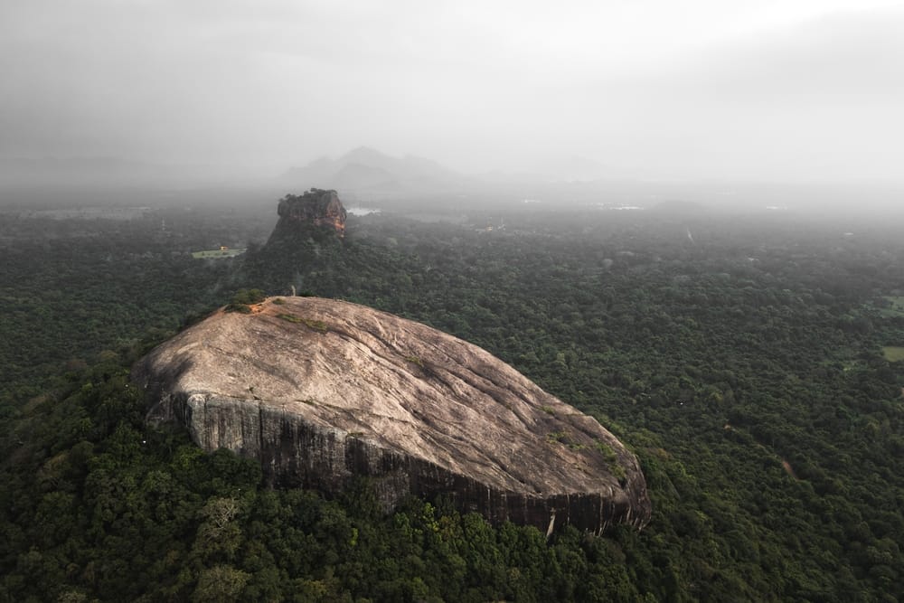 Luftfoto af vandrere på toppen af Pidurangala Rock med udsigt over Sigiriya og junglen i Sri Lanka.
