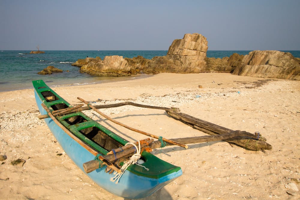 Paradisstrand ved Trincomalee med klart blåt vand og en båd på sandet