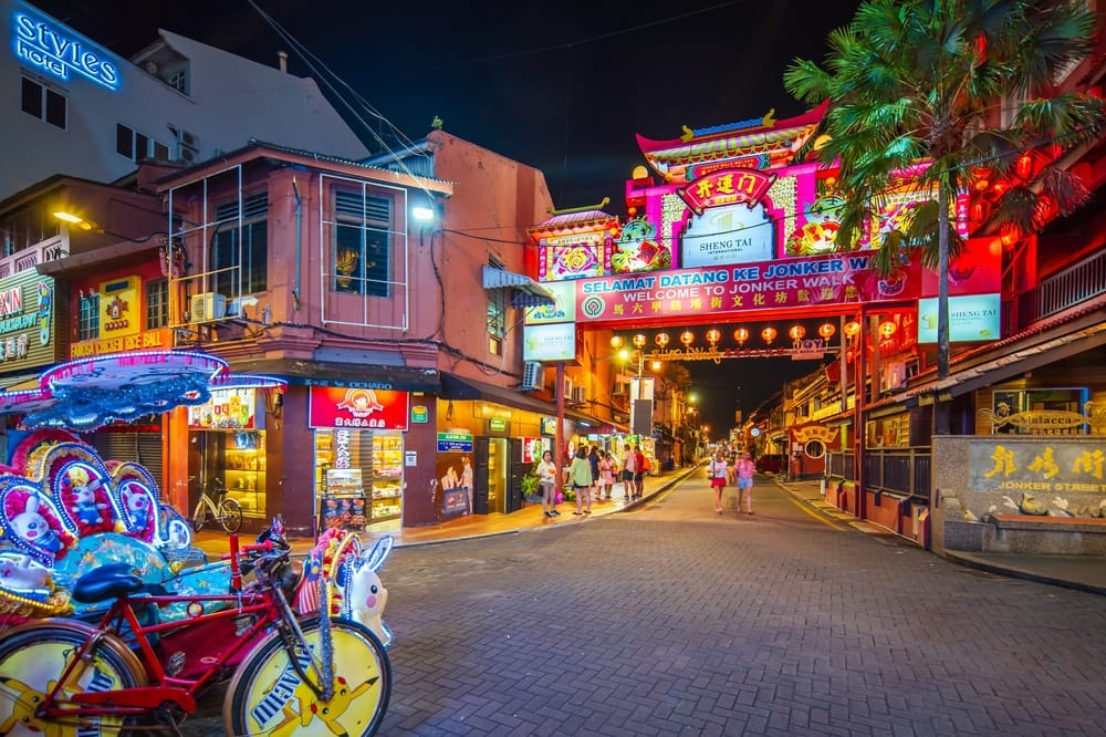 Jonker Street i Malacca om aftenen med farverige lys, butikker og kinesisk port.