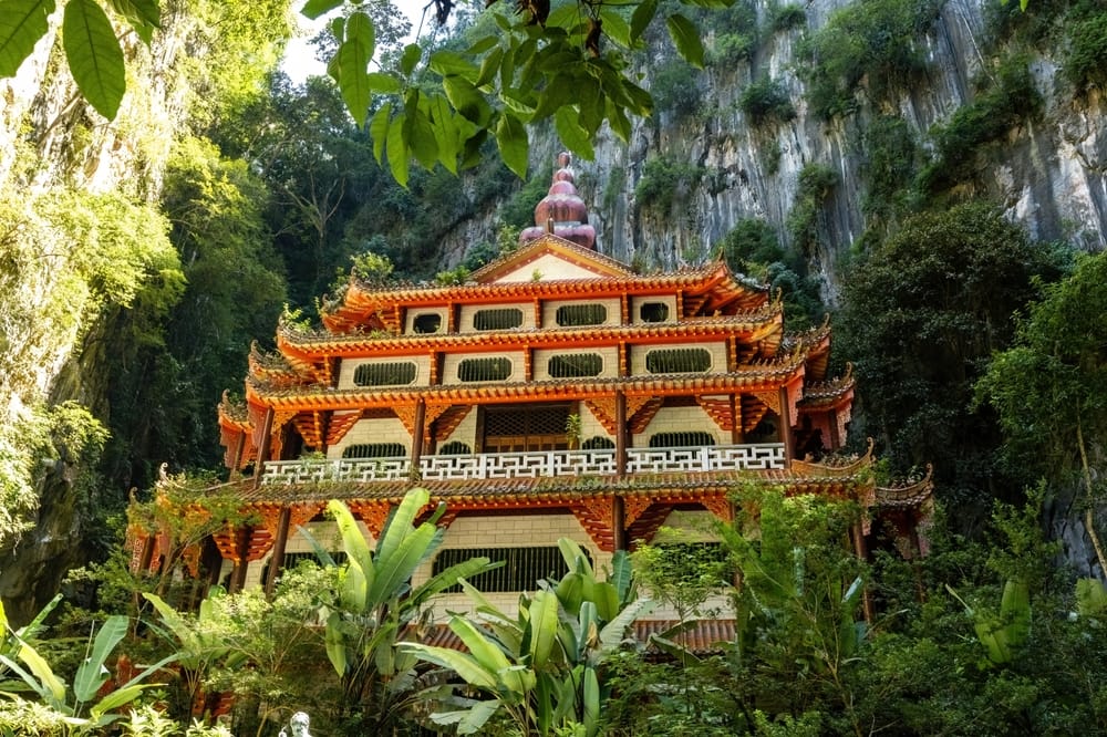 Kinesisk tempel ved kalkstensklippe omgivet af frodig vegetation i Ipoh, Malaysia.