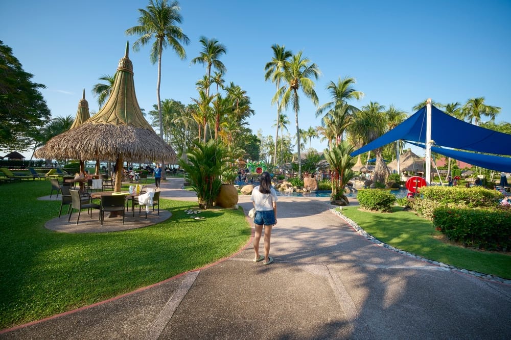 Mennesker der går langs strandpromenade i Penang, Malaysia, med havet i baggrunden.