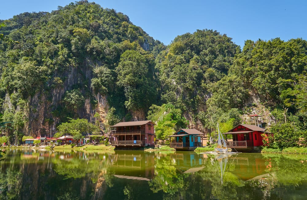 Træhus ved sø i Ipoh omgivet af grønne kalkstensklipper i Perak, Malaysia.