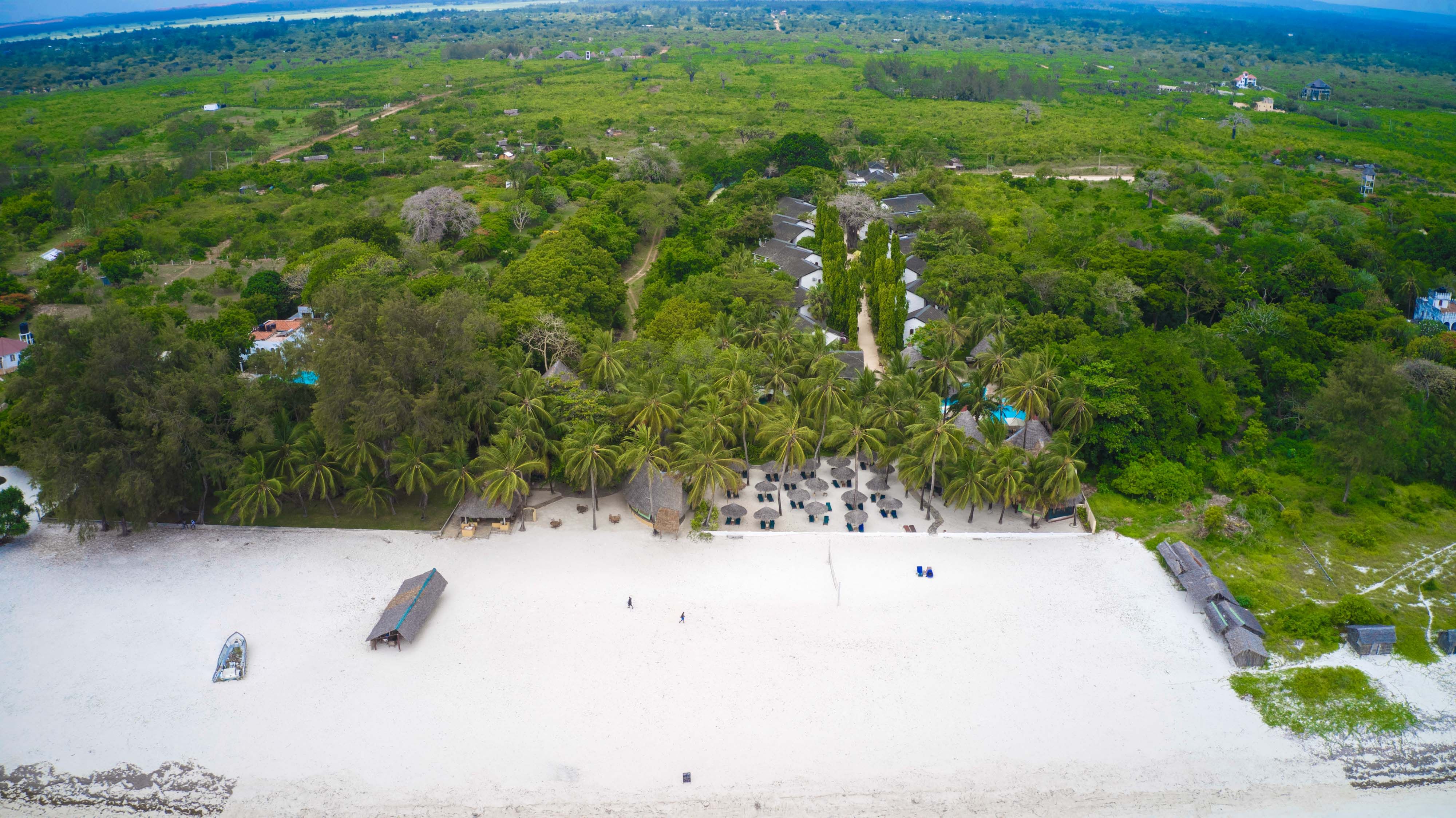 Luftfoto af Pinewood Beach and Spa Resort omgivet af palmer og strand